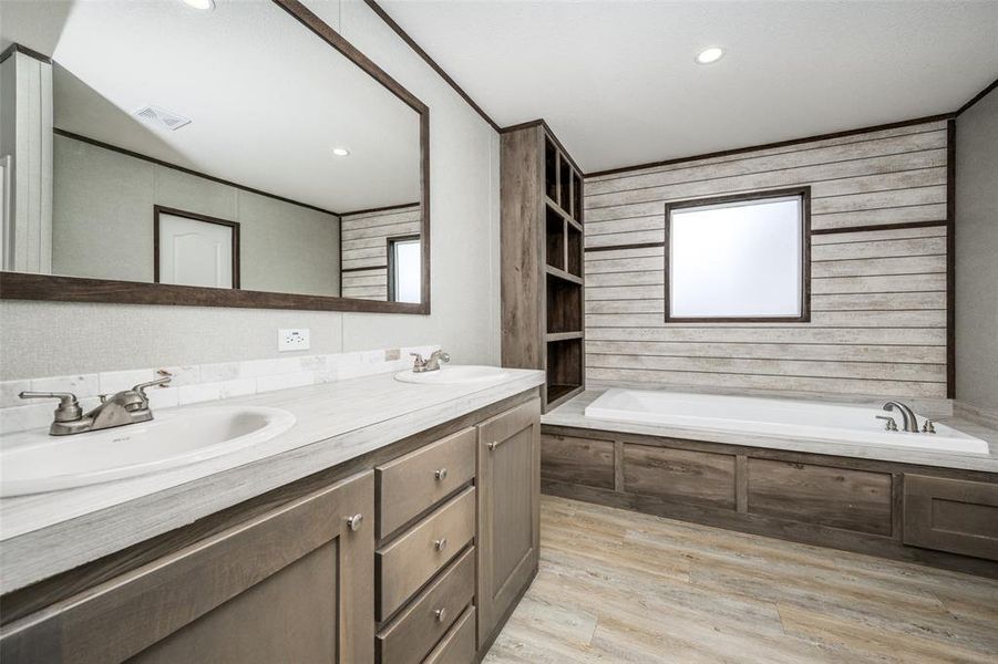 Full bath with a garden tub, double vanity, and light wood-style flooring Full bath with a garden tub, double vanity, and light wood-style flooring