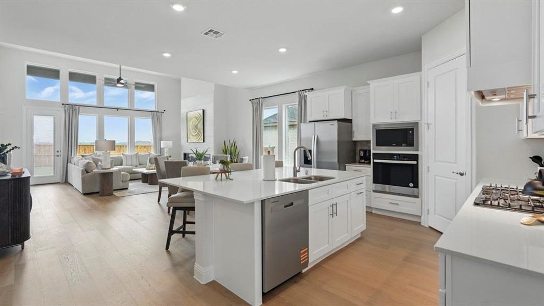 Kitchen with white cabinetry, light wood-type flooring, stainless steel appliances, open floor plan, and recessed lighting