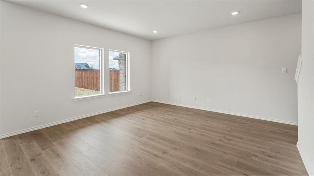 This spacious room features light wood-style flooring, white walls, and recessed lighting