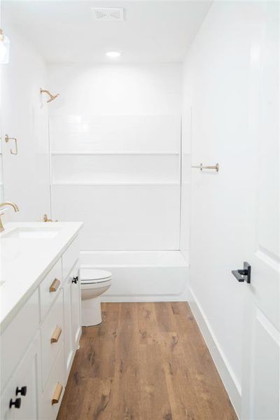 Full bathroom with hardwood / wood-style flooring, vanity, toilet, and shower / tub combination