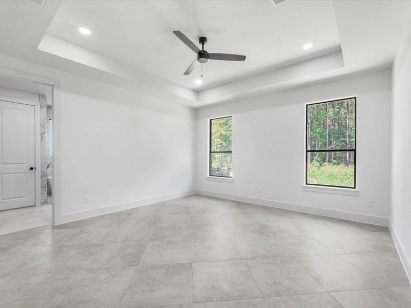 Primary bedroom features tray ceilings and a fan for extra comfort. The tile flooring throughout the home ties it together.