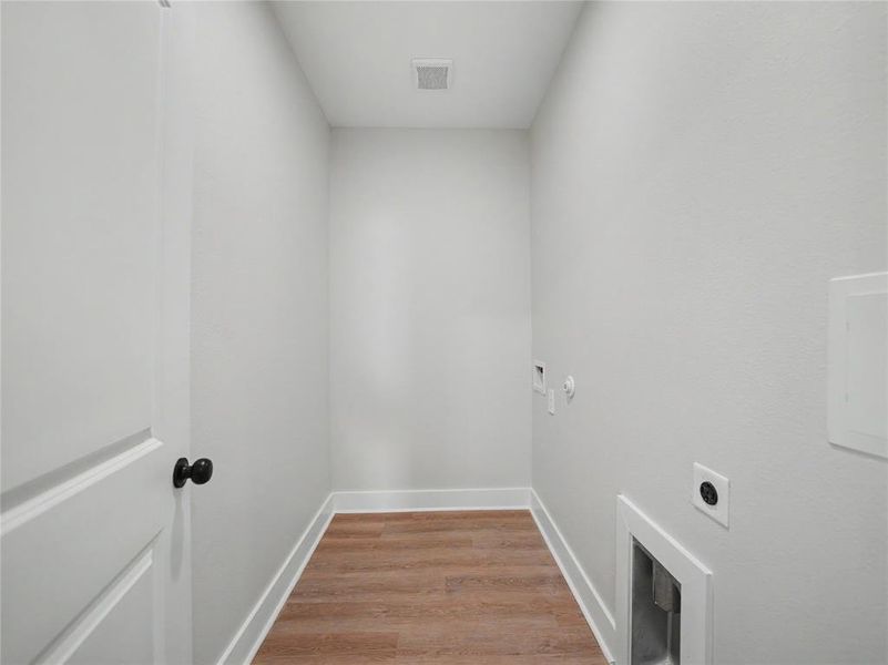 Utility room with wood-finish flooring, light gray walls, white baseboards, and a white ceiling Utility room with wood-finish flooring, light gray walls, white baseboards, and a white ceiling