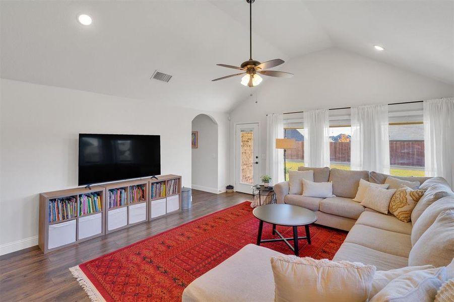 Living room with ceiling fan, dark hardwood / wood-style flooring, and vaulted ceiling