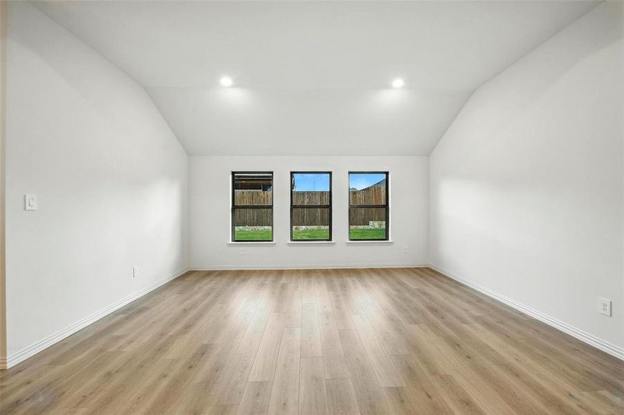 Empty room featuring lofted ceiling, light wood-type flooring, and recessed lighting