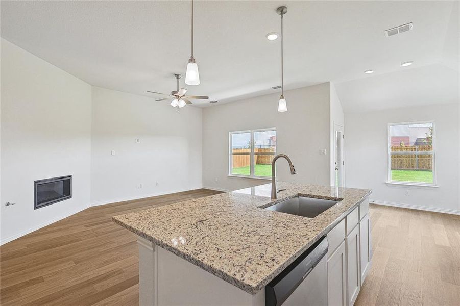 Kitchen featuring a kitchen island with sink, stainless steel dishwasher, sink, and light hardwood / wood-style floors