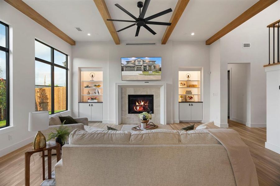 Living area featuring a ceiling fan, a tile fireplace, light wood finished floors, recessed lighting, and beamed ceiling Living area featuring a ceiling fan, a tile fireplace, light wood finished floors, recessed lighting, and beamed ceiling