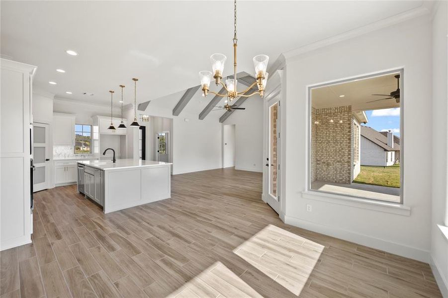 Kitchen featuring a chandelier, open floor plan, an island with sink, decorative light fixtures, and wood finish floors