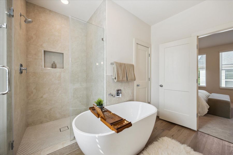 A freestanding soaking tub takes center stage—perfect for unwinding after a long day—while the frameless glass shower features elegant tilework and a built-in niche for added convenience.
