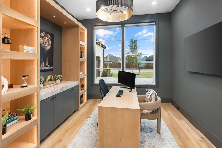 Private study designed for both productivity and style, featuring custom built-in shelving with accent lighting and integrated cabinetry. Real hardwood floors, designer lighting, and large windows providing natural light create an inspiring and sophisticated workspace.