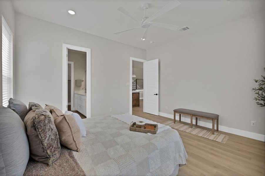 Bedroom with light wood finished floors, baseboards, ceiling fan, ensuite bath, and recessed lighting Bedroom with light wood finished floors, baseboards, ceiling fan, ensuite bath, and recessed lighting