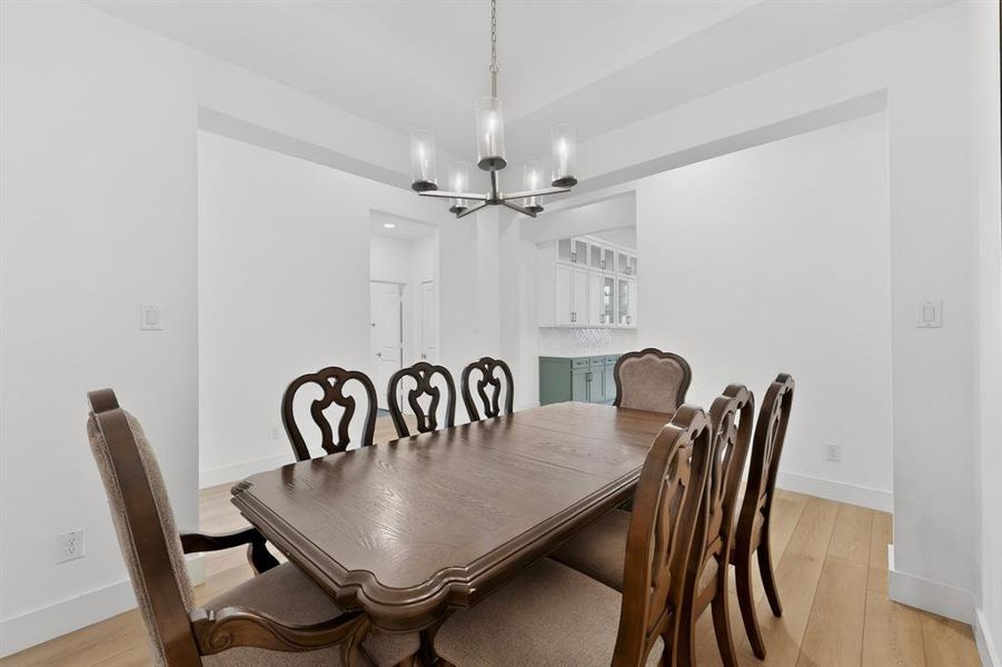 Dining area featuring light wood-finish flooring and a contemporary chandelier Dining area featuring light wood-finish flooring and a contemporary chandelier