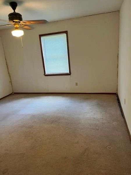 Room featuring a ceiling fan with integrated lighting, wall-mounted window with blinds, and carpeted flooring Room featuring a ceiling fan with integrated lighting, wall-mounted window with blinds, and carpeted flooring