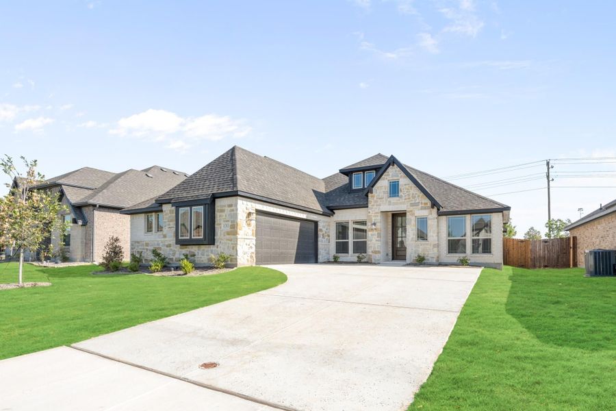 Single-story home with stone and brick exterior, two-car garage, and green front lawn Single-story home with stone and brick exterior, two-car garage, and green front lawn