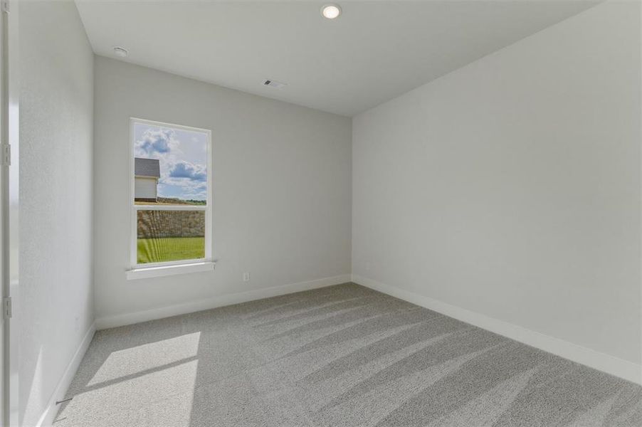 Bright interior room featuring a window overlooking a green expanse and stone wall Bright interior room featuring a window overlooking a green expanse and stone wall