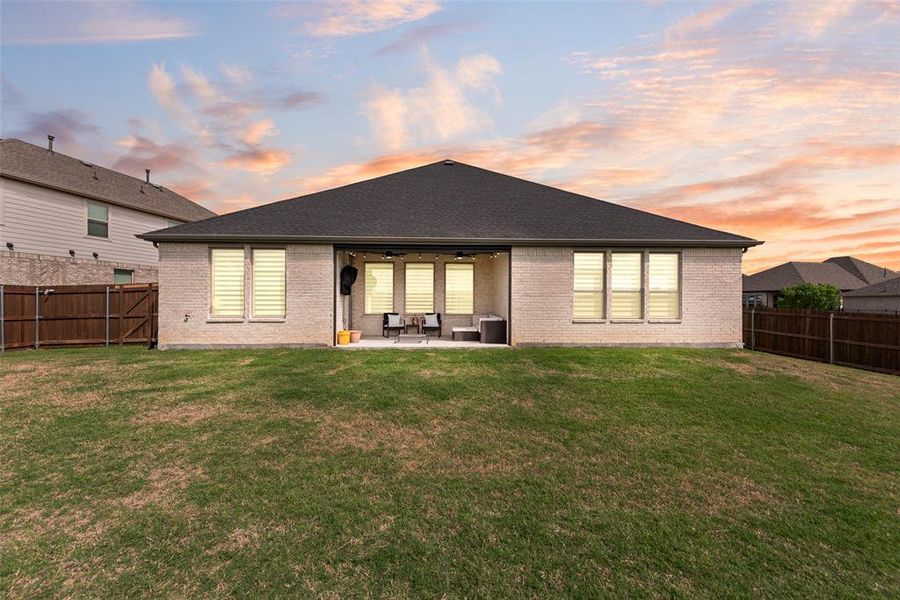 Spacious backyard featuring a covered patio, extensive lawn, and a full privacy fence
