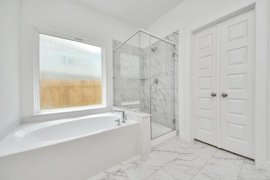 Escape to a spa-like oasis in this primary bathroom. Enjoy a walk-in shower with tile surround, a separate garden tub with custom detailing, and an elegant vanity featuring light countertops, modern hardware, and beautiful recessed lights. Experience luxury and relaxation in every detail. Escape to a spa-like oasis in this primary bathroom. Enjoy a walk-in shower with tile surround, a separate garden tub with custom detailing, and an elegant vanity featuring light countertops, modern hardware, and beautiful recessed lights. Experience luxury and relaxation in every detail.