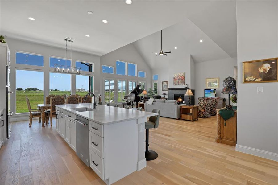 Kitchen with a chandelier, a sink, high vaulted ceiling, dishwasher, and white cabinetry Kitchen with a chandelier, a sink, high vaulted ceiling, dishwasher, and white cabinetry