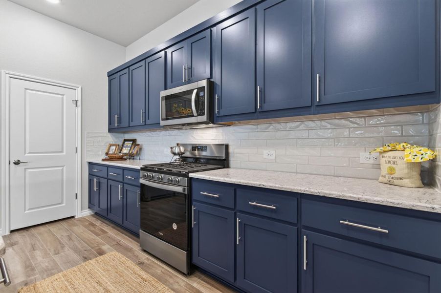 Elegant blue cabinetry and gleaming countertops define this well-appointed kitchen. Elegant blue cabinetry and gleaming countertops define this well-appointed kitchen.