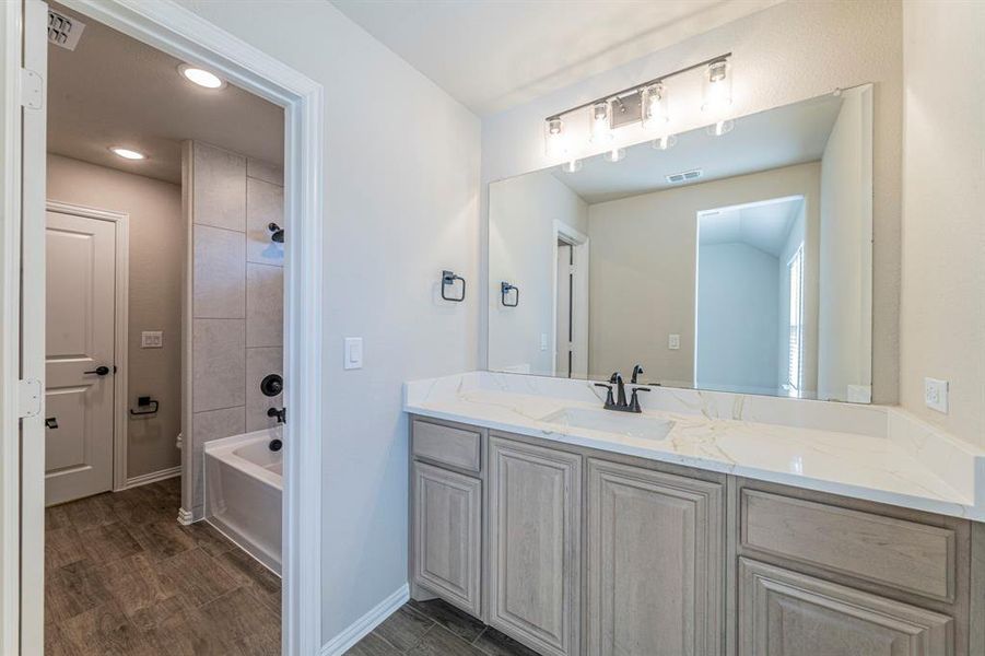 Bathroom featuring a light-toned vanity with a white countertop, an undermount sink, and a matte black faucet
