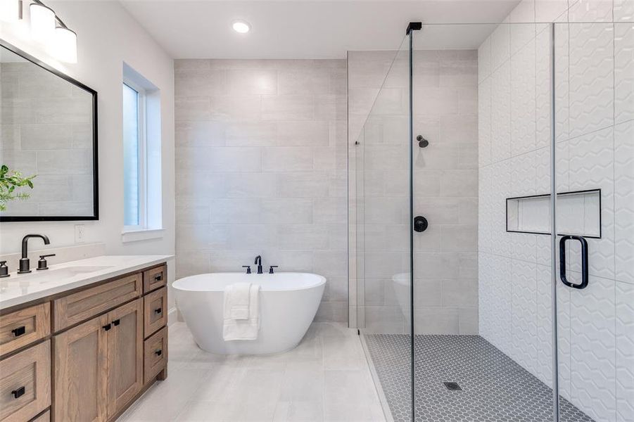 Spa-like primary bathroom with a freestanding bath, a large walk-in shower, double vanity, tile walls, and recessed lighting Spa-like primary bathroom with a freestanding bath, a large walk-in shower, double vanity, tile walls, and recessed lighting
