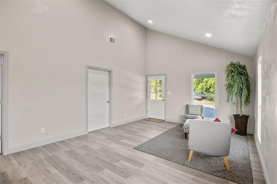 Living area with light wood finished floors, recessed lighting, and vaulted ceiling