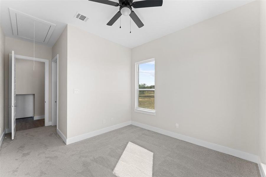 Unfurnished bedroom featuring attic access, carpet floors, and a ceiling fan Unfurnished bedroom featuring attic access, carpet floors, and a ceiling fan