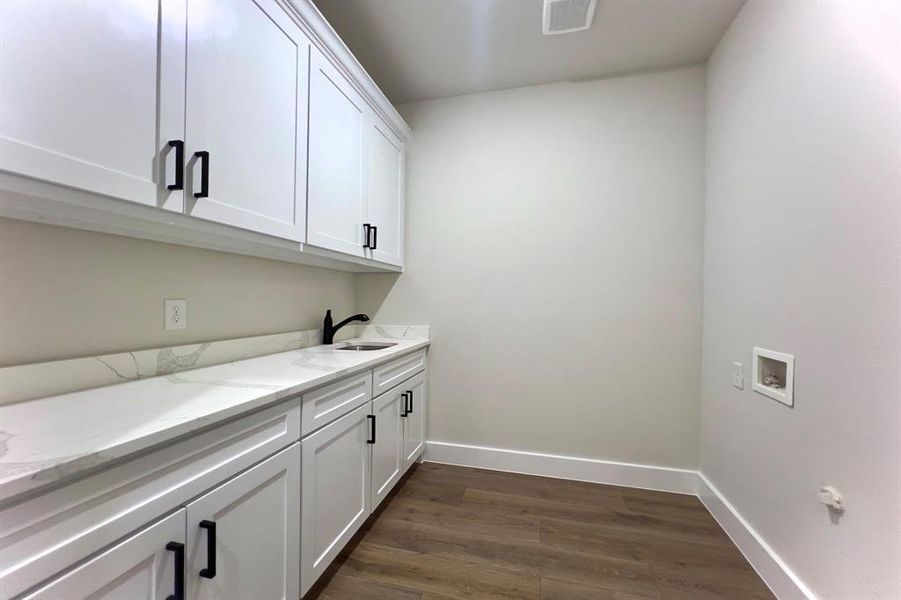 Laundry room featuring dark floors, hookup for a washing machine, and cabinet space