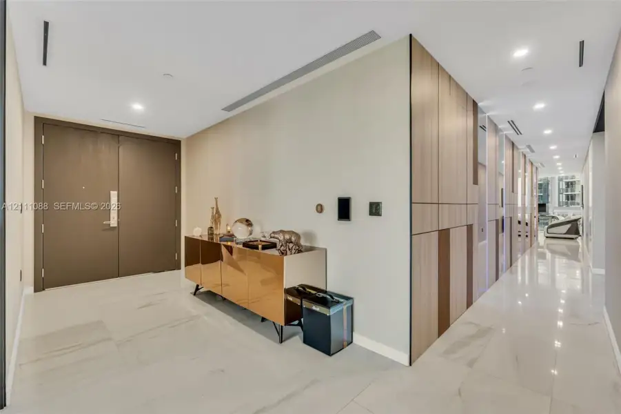 Entryway featuring large-format stone tile flooring, floor-to-ceiling wood-finish paneling, recessed ceiling lighting, and custom double doors Entryway featuring large-format stone tile flooring, floor-to-ceiling wood-finish paneling, recessed ceiling lighting, and custom double doors