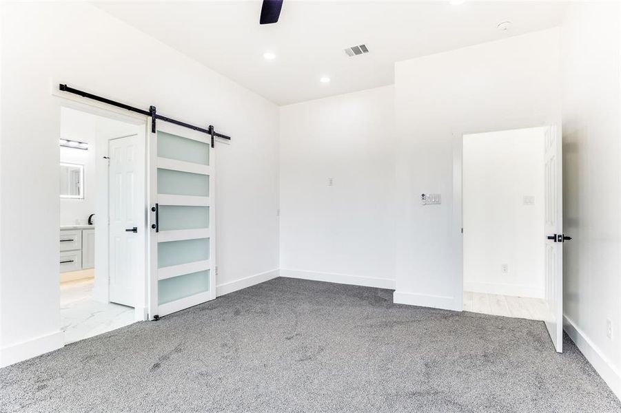 Unfurnished room with a barn door, light carpet, recessed lighting, and a ceiling fan Unfurnished room with a barn door, light carpet, recessed lighting, and a ceiling fan