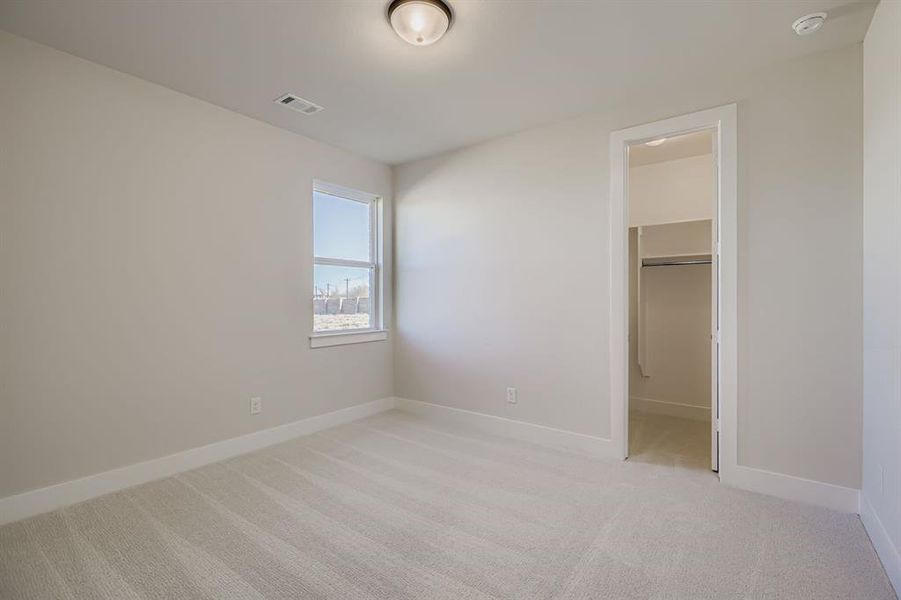 Unfurnished bedroom with light carpet and a spacious closet