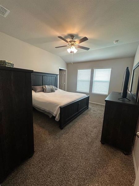 Bedroom featuring dark carpet, ceiling fan, and vaulted ceiling