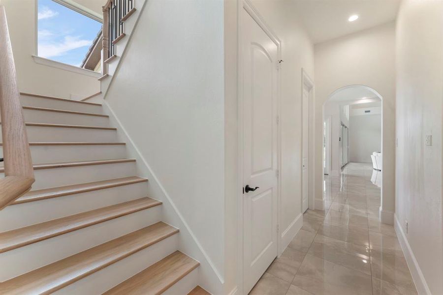 Bright, clean entryway with a 2nd wooden staircase. That 1st door is an incredible storage closet the wraps under the staircase.