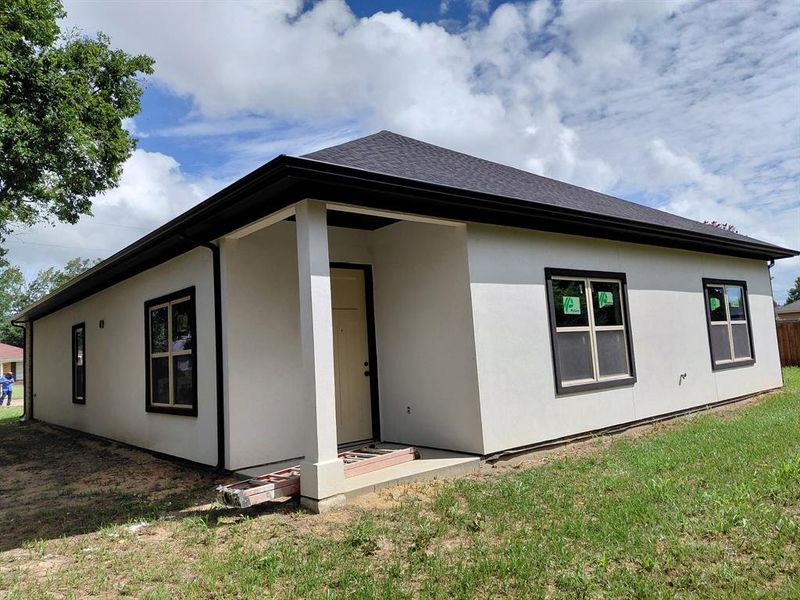 Back of property with stucco siding and a yard