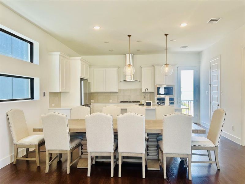Kitchen featuring white cabinets, decorative light fixtures, backsplash, an island with sink, and recessed lighting Kitchen featuring white cabinets, decorative light fixtures, backsplash, an island with sink, and recessed lighting