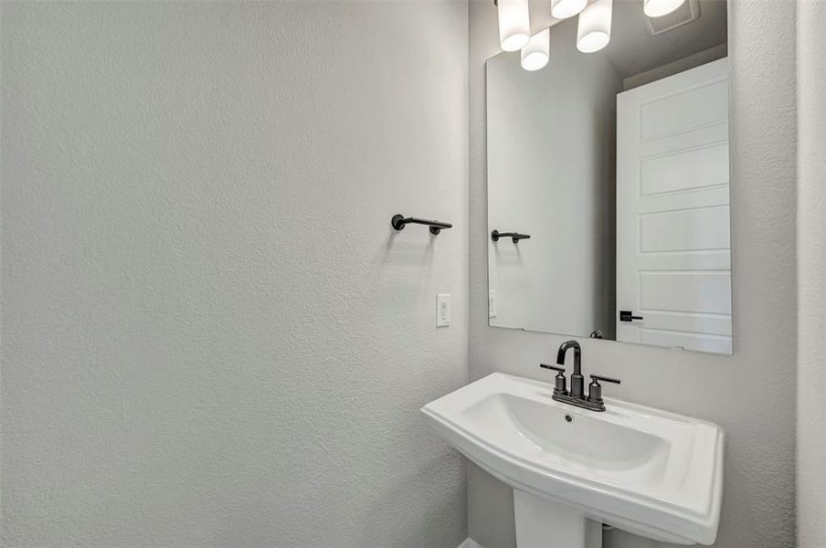 Bathroom featuring a sink and a textured wall Bathroom featuring a sink and a textured wall