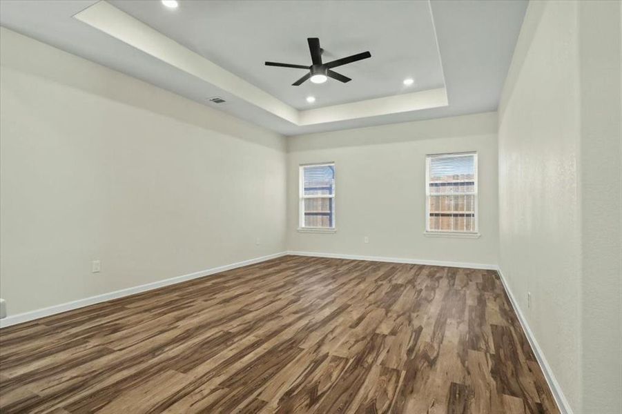 Unfurnished room featuring a raised ceiling, dark wood-style flooring, ceiling fan, and recessed lighting Unfurnished room featuring a raised ceiling, dark wood-style flooring, ceiling fan, and recessed lighting