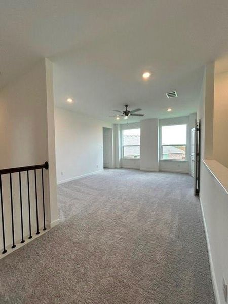 Spacious room featuring neutral carpeting, recessed lighting, a ceiling fan, and multiple windows providing natural light Spacious room featuring neutral carpeting, recessed lighting, a ceiling fan, and multiple windows providing natural light