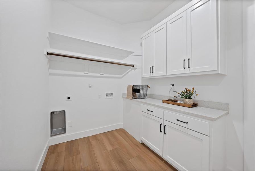 Bright laundry space featuring white shaker cabinetry with black hardware