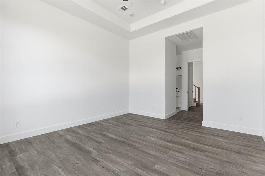 Unfurnished room featuring wood finished floors and a tray ceiling Unfurnished room featuring wood finished floors and a tray ceiling