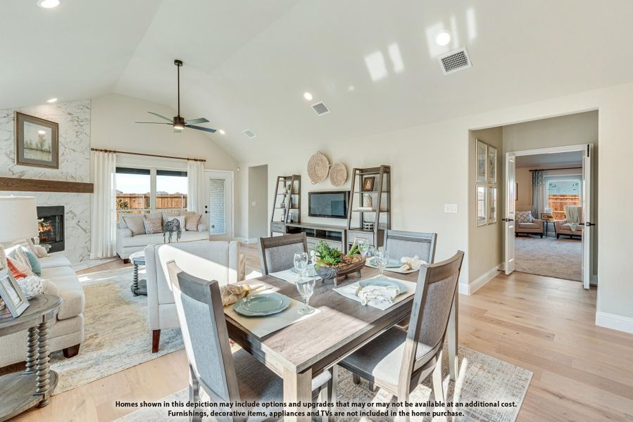 Open-plan dining and living area with vaulted ceiling, stone fireplace, and hardwood floors Open-plan dining and living area with vaulted ceiling, stone fireplace, and hardwood floors