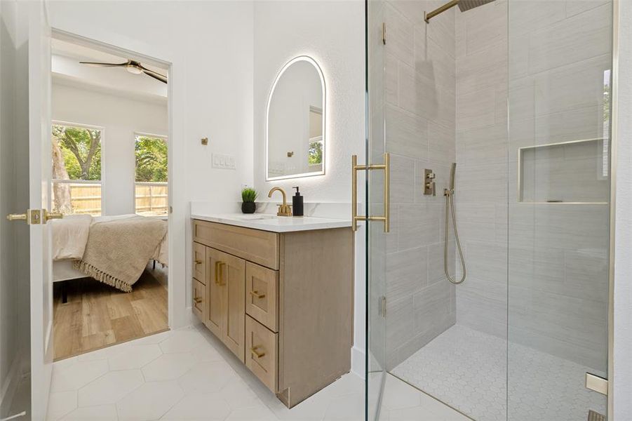 Bathroom featuring a single vanity with stone countertop, light wood-finish cabinetry, and gold-tone hardware Bathroom featuring a single vanity with stone countertop, light wood-finish cabinetry, and gold-tone hardware