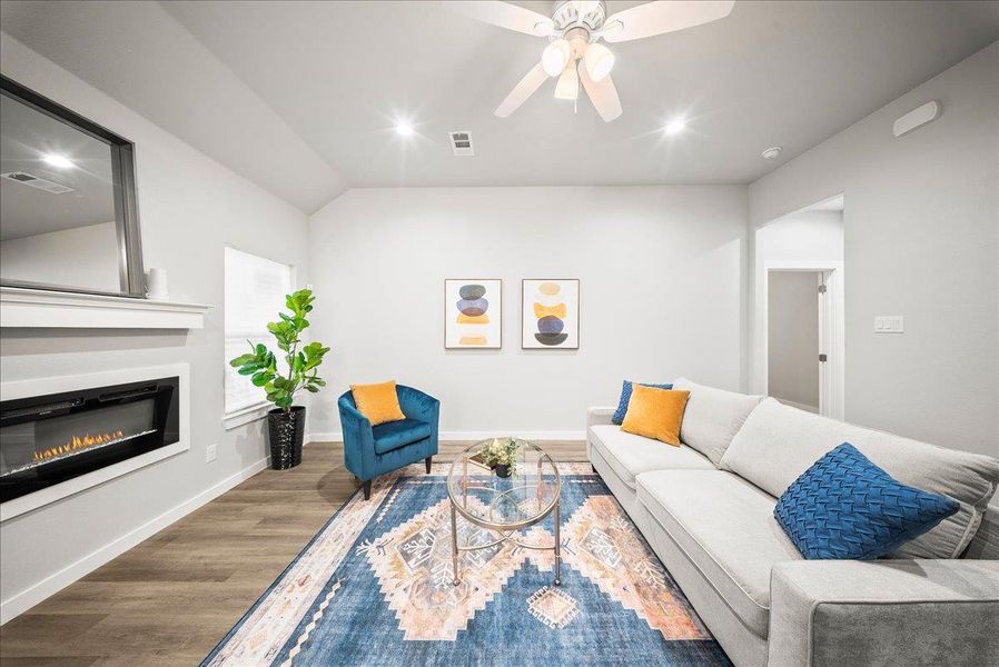 Living room with wood finished floors, recessed lighting, a glass covered fireplace, a ceiling fan, and vaulted ceiling Living room with wood finished floors, recessed lighting, a glass covered fireplace, a ceiling fan, and vaulted ceiling