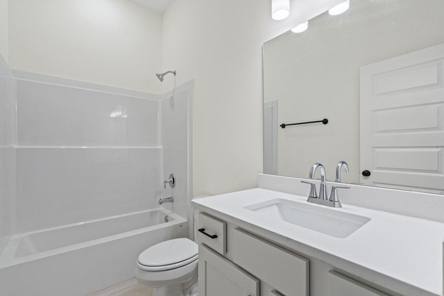 Bathroom featuring a white integrated sink vanity with a white countertop and chrome faucet Bathroom featuring a white integrated sink vanity with a white countertop and chrome faucet