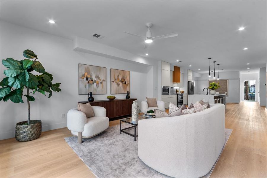 Open-concept living area with light wood-finish flooring, recessed lighting, and a modern ceiling fan Open-concept living area with light wood-finish flooring, recessed lighting, and a modern ceiling fan