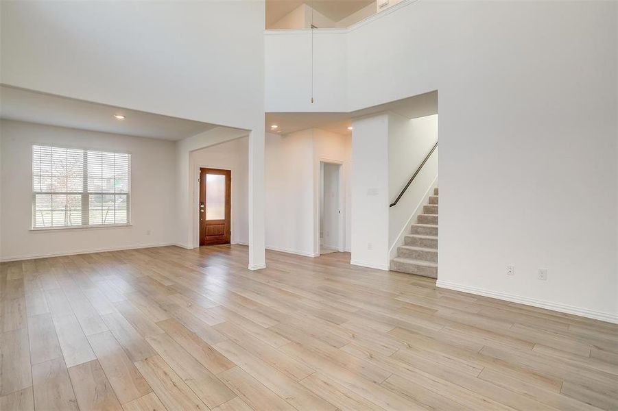 Unfurnished living room featuring a towering ceiling and light hardwood / wood-style flooring