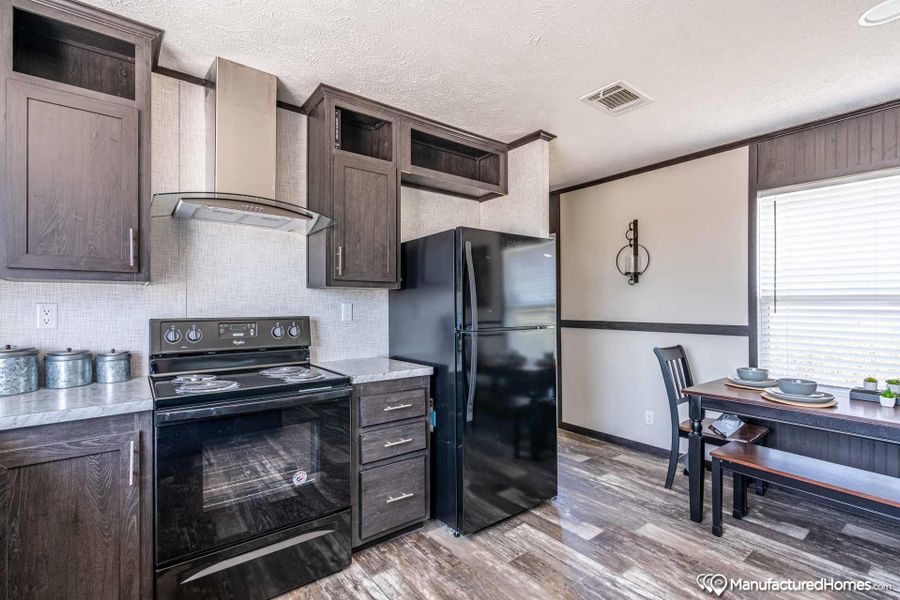 Prepare meals in this kitchen featuring a black range and refrigerator, with ample cabinetry.