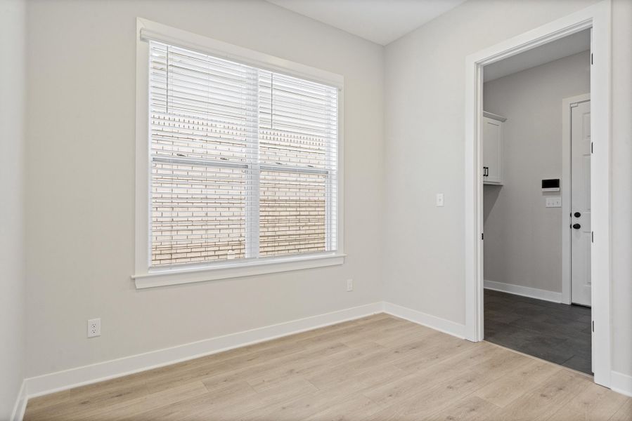 Neutral-toned room featuring light wood-finish flooring, a double window with blinds, and white trim Neutral-toned room featuring light wood-finish flooring, a double window with blinds, and white trim
