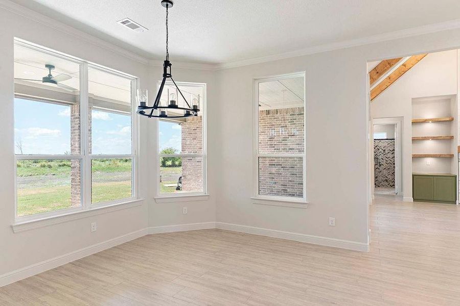 Unfurnished dining area featuring light wood-type flooring, a chandelier, and crown molding