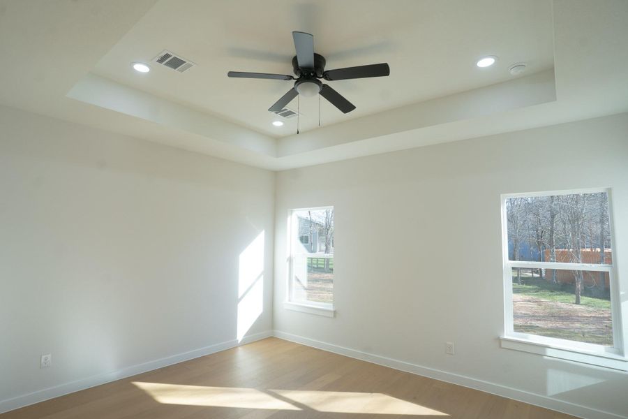Spare room featuring a tray ceiling, wood finished floors, a ceiling fan, and recessed lighting