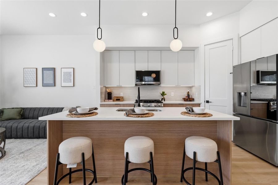 White uppers and wood-toned lowers create a balanced, modern aesthetic. A neutral tile backsplash and black fixtures provide a refined architectural finish.